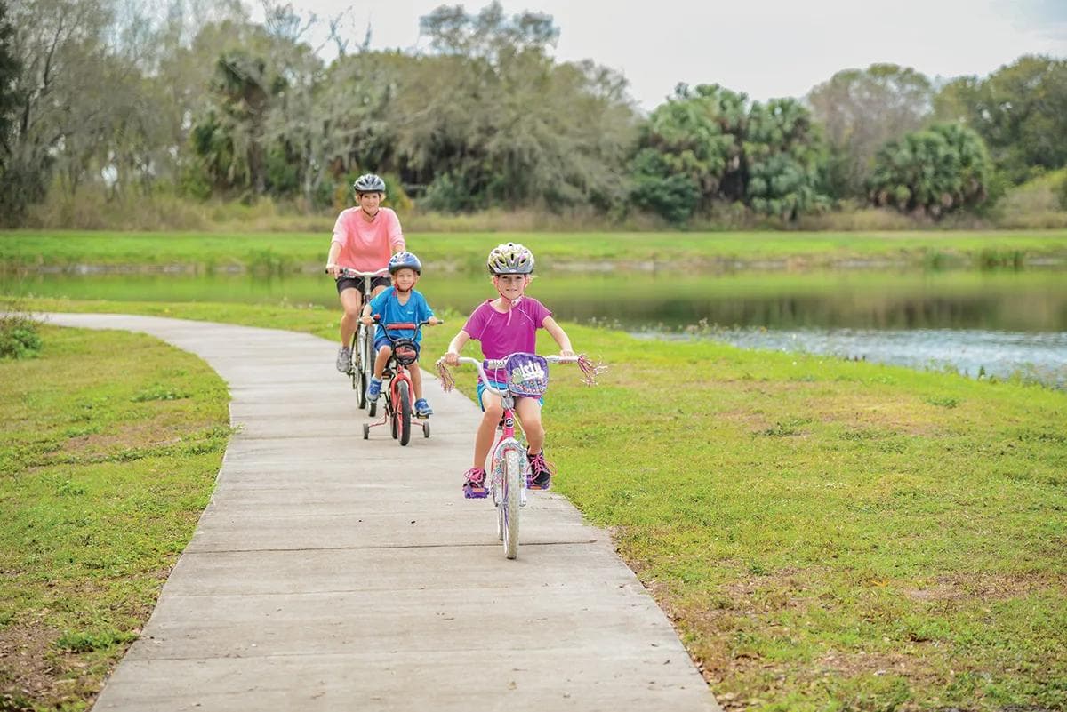 Family riding bikes on a boardwalk trail at GreyHawk Landing, Bradenton FL