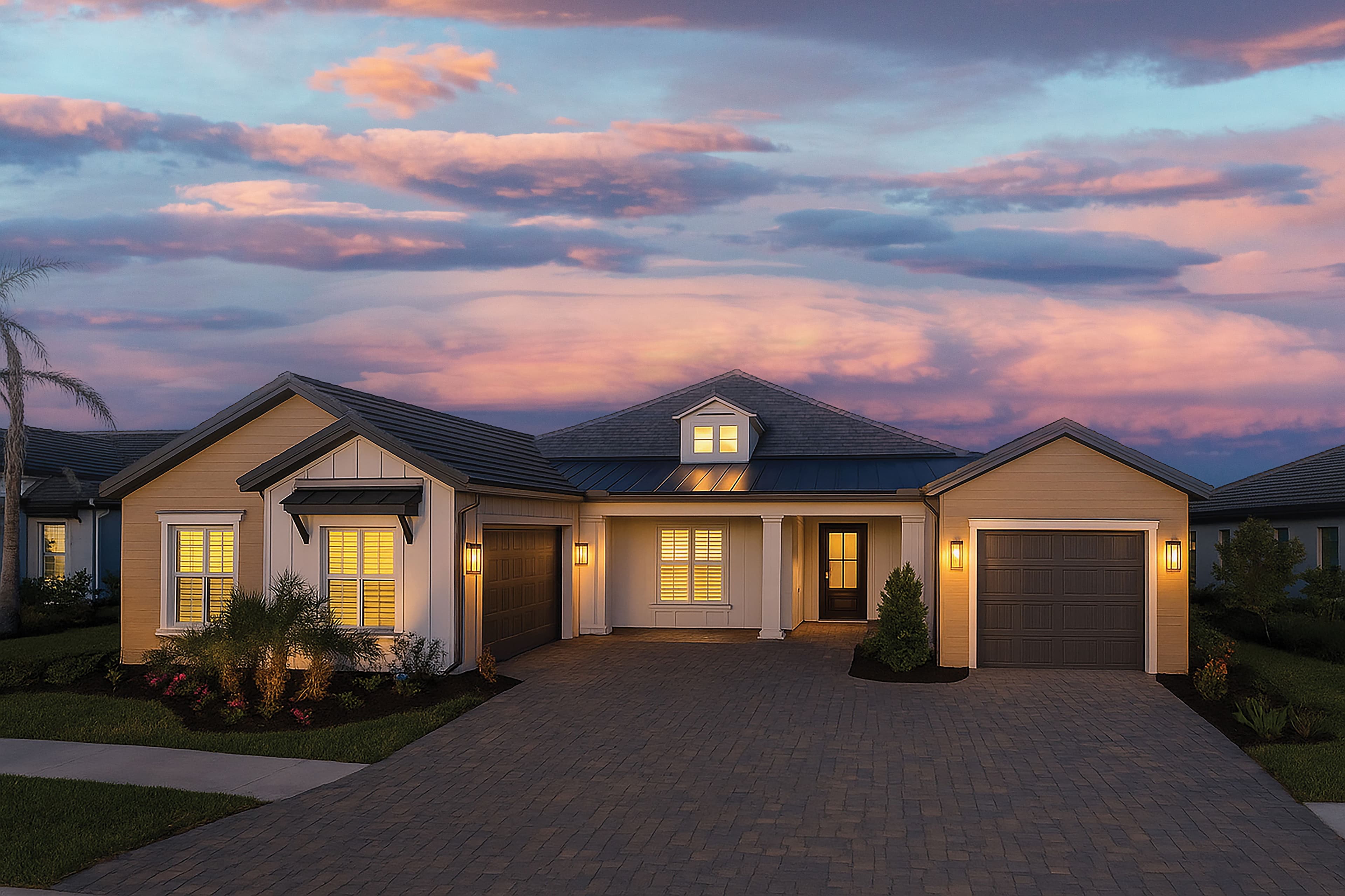 A Sam Rodgers home glowing at twilight under a pink Gulf Coast sky, paver drive leading to the front porch
