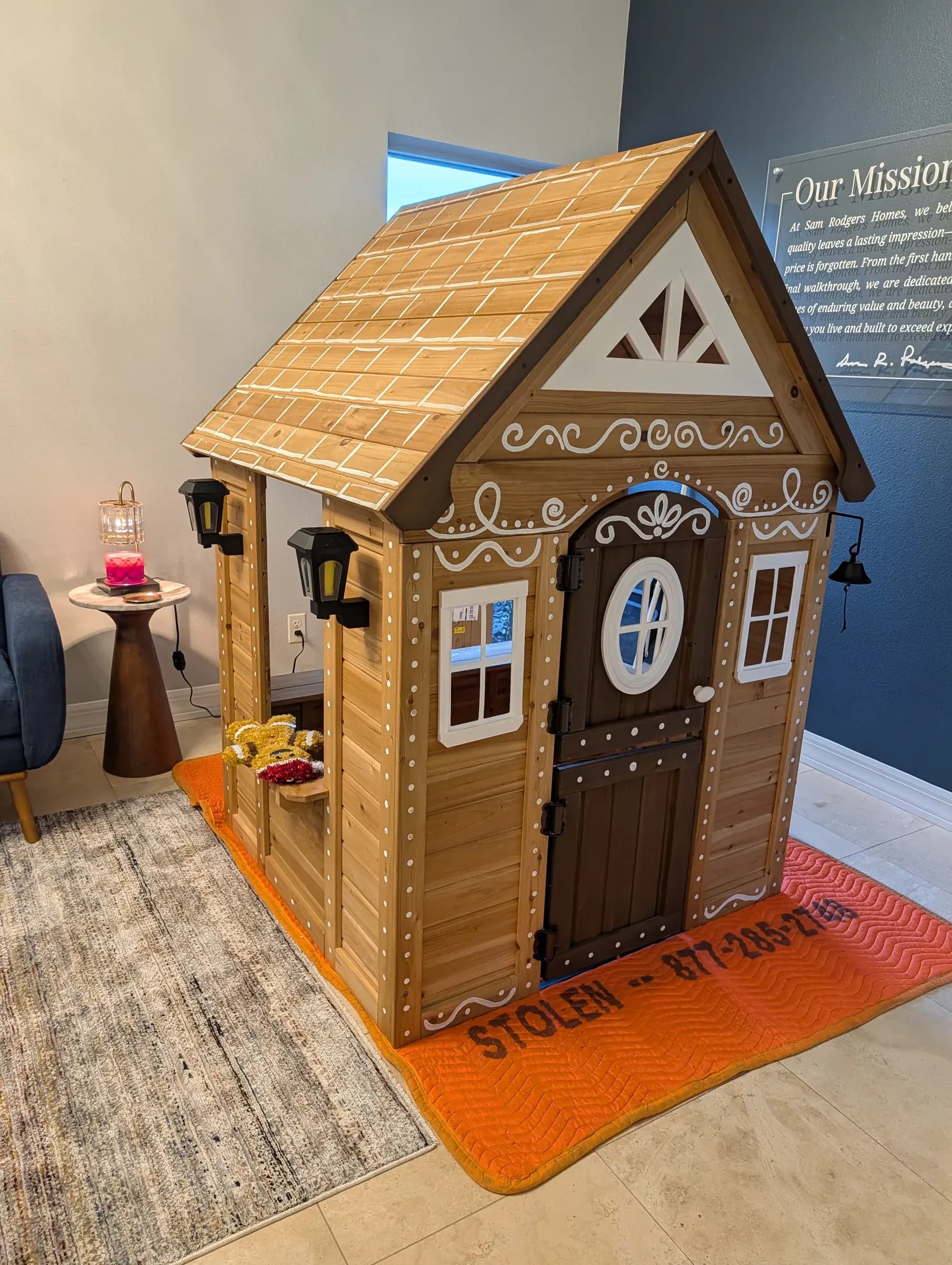 The finished playhouse indoors, with its round window and carriage lanterns.