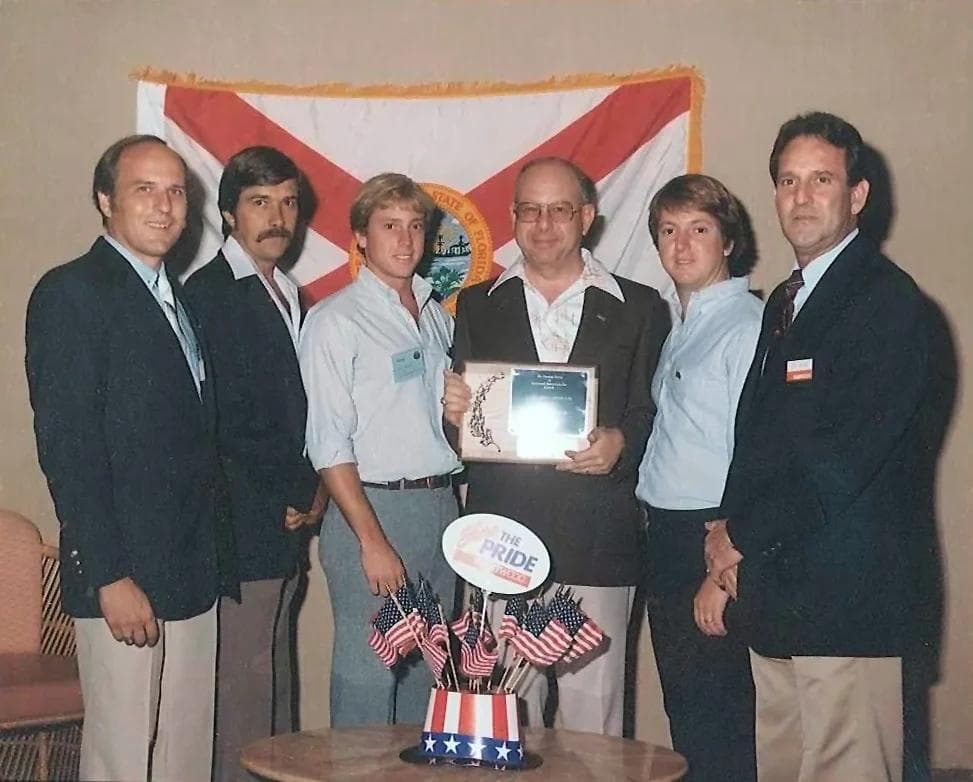 The Sam Rodgers team accepting an industry award beside a Florida state flag